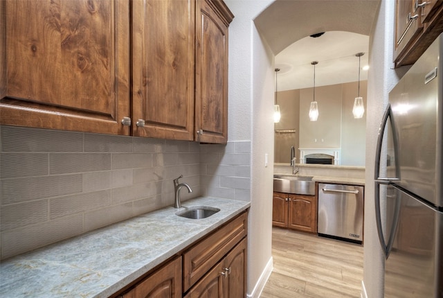 kitchen featuring sink, light stone countertops, stainless steel appliances, and light wood-type flooring