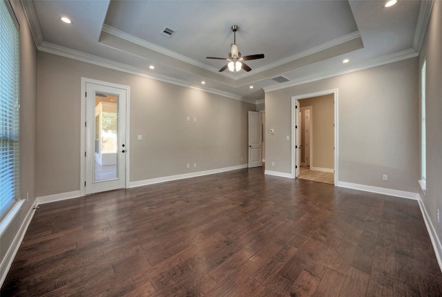 empty room featuring crown molding, a raised ceiling, and dark hardwood / wood-style flooring