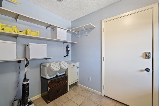 laundry room featuring a textured ceiling and light tile patterned flooring