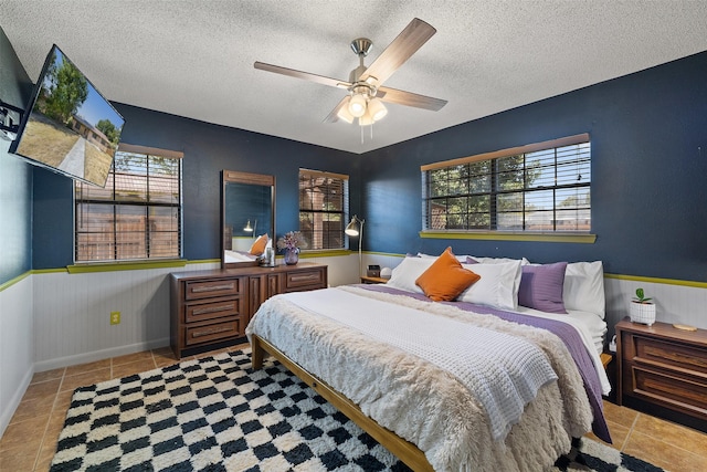 bedroom with multiple windows, ceiling fan, light tile patterned floors, and a textured ceiling