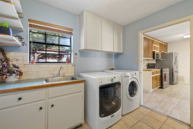 laundry room with cabinets, a textured ceiling, sink, light tile patterned floors, and independent washer and dryer