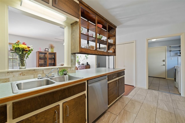 kitchen with stainless steel dishwasher, separate washer and dryer, sink, and light tile patterned floors