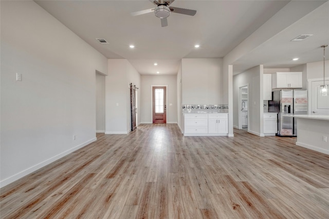 unfurnished living room featuring ceiling fan and light wood-type flooring