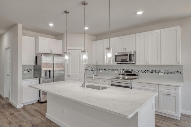 kitchen with white cabinets, an island with sink, sink, light hardwood / wood-style floors, and stainless steel appliances