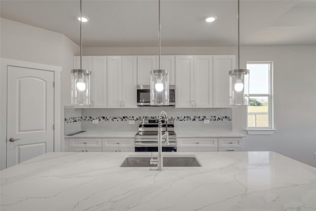 kitchen featuring appliances with stainless steel finishes, white cabinetry, light stone countertops, and backsplash