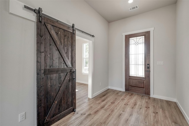 foyer featuring light hardwood / wood-style floors, a healthy amount of sunlight, and a barn door