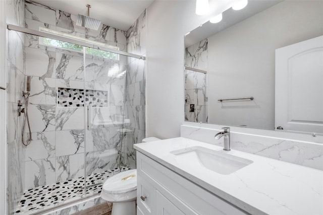 bathroom with vanity, a shower with shower door, and toilet