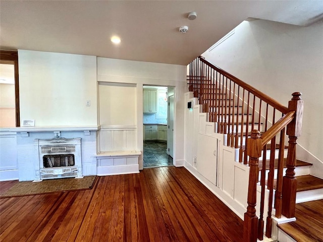 unfurnished living room featuring heating unit, wood-type flooring, and stairs