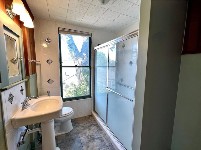 bathroom with a stall shower, plenty of natural light, tile walls, and toilet