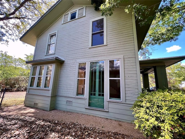 rear view of house with crawl space and fence