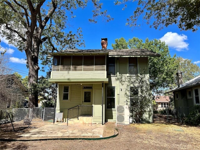 view of front of home with a sunroom, fence, a chimney, and a gate