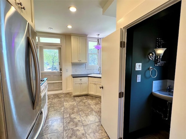 kitchen with a wealth of natural light, a sink, freestanding refrigerator, and decorative backsplash