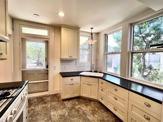 314 Pershing Ave, San Antonio, TX 78209 - kitchen featuring tasteful backsplash, range with gas stovetop, dark countertops, a sink, and hanging light fixtures
