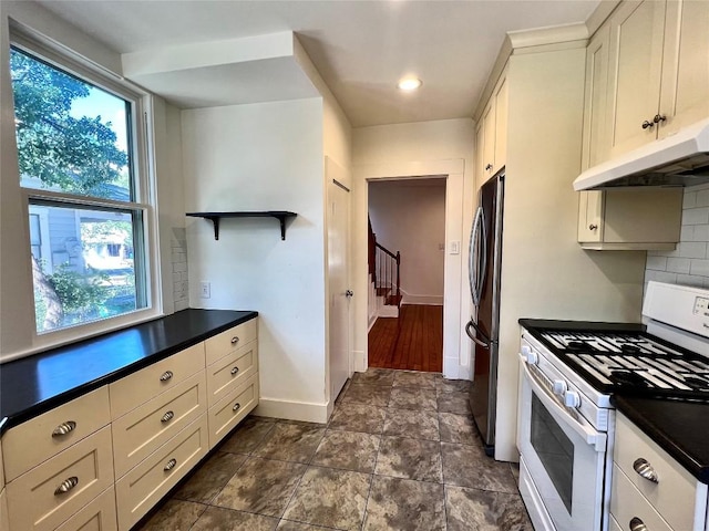 kitchen featuring white range with gas stovetop, freestanding refrigerator, open shelves, tasteful backsplash, and dark countertops