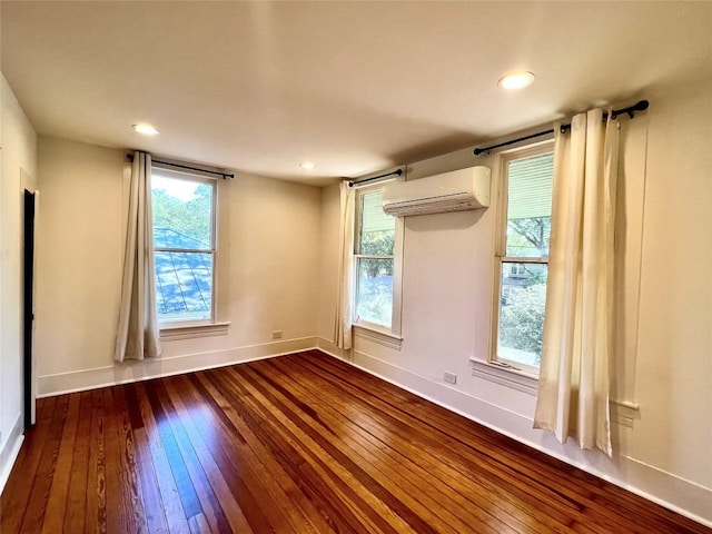 unfurnished room featuring an AC wall unit, dark wood-style flooring, recessed lighting, and baseboards