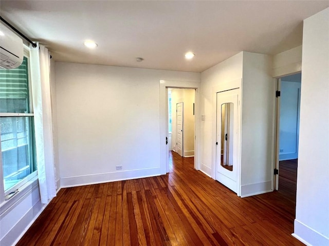 empty room with recessed lighting, wood-type flooring, baseboards, and a wall mounted air conditioner