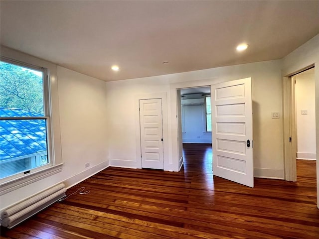 unfurnished room featuring recessed lighting, a baseboard radiator, wood finished floors, and baseboards