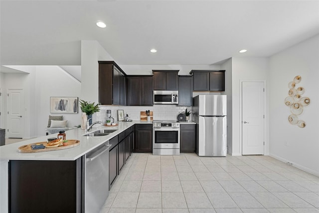 kitchen featuring decorative backsplash, kitchen peninsula, stainless steel appliances, sink, and light tile patterned flooring