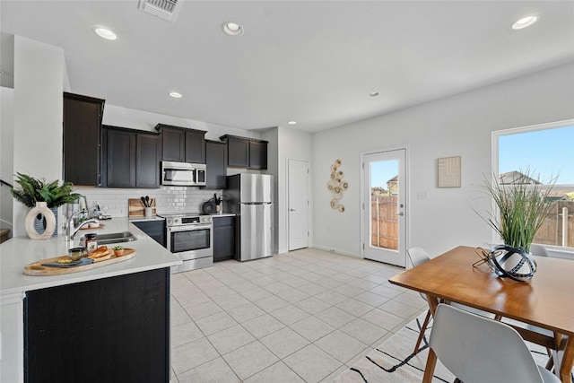 kitchen with backsplash, appliances with stainless steel finishes, sink, and light tile patterned floors