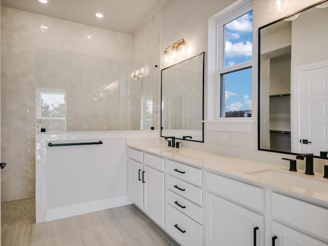 bathroom with a tile shower and vanity