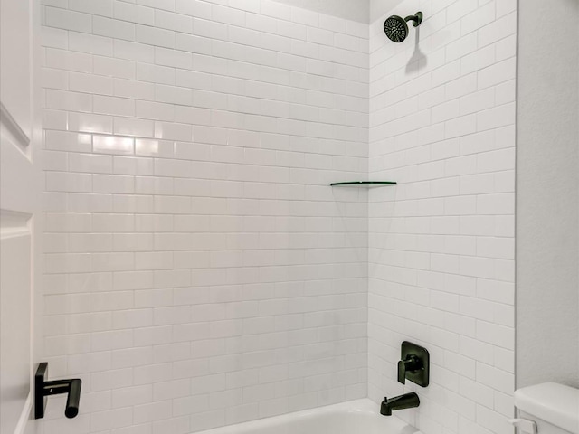 bathroom featuring tiled shower / bath combo and toilet