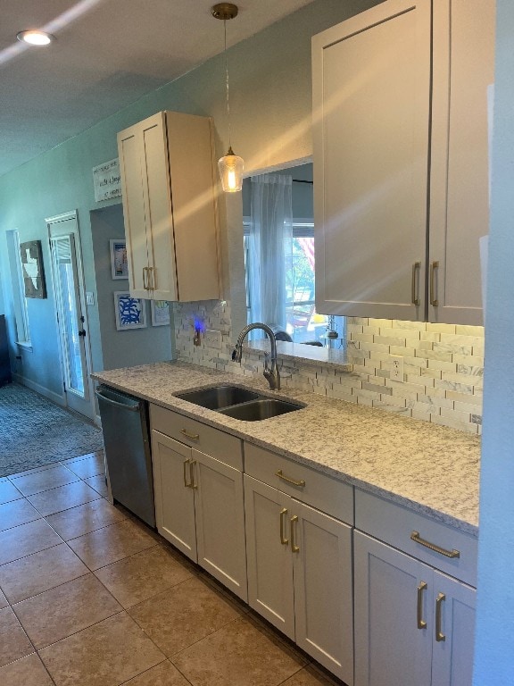 kitchen featuring sink, dishwasher, decorative light fixtures, light stone counters, and light tile patterned floors