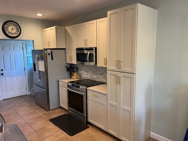 kitchen with decorative backsplash, appliances with stainless steel finishes, white cabinetry, and light tile patterned floors