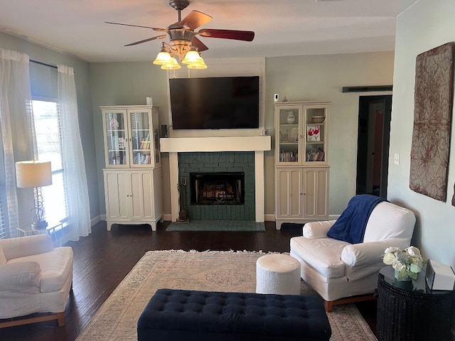 living room featuring ceiling fan, dark hardwood / wood-style flooring, and a fireplace