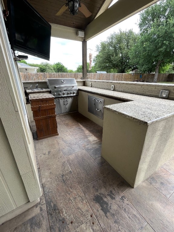 view of patio / terrace with exterior kitchen, a grill, and ceiling fan