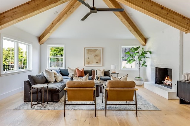 living room featuring beam ceiling, high vaulted ceiling, light hardwood / wood-style flooring, and a brick fireplace