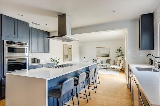 2900 Windsor Rd, Austin, TX 78703 - kitchen featuring a sink, island exhaust hood, stainless steel appliances, backsplash, and light wood-style flooring