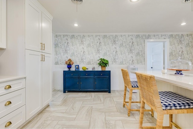 kitchen with white cabinetry, light stone countertops, ornamental molding, and blue cabinets