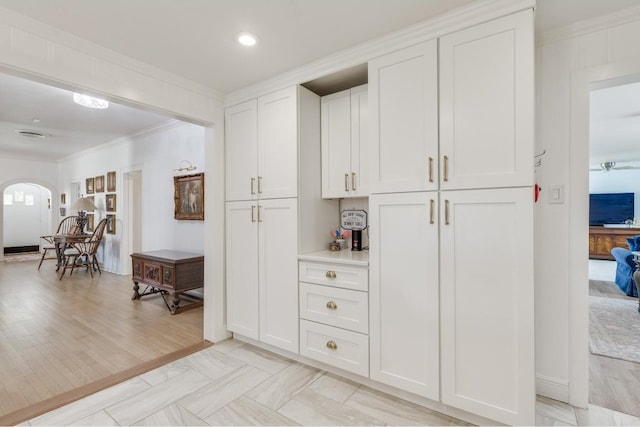 kitchen featuring crown molding, white cabinets, and light wood-type flooring