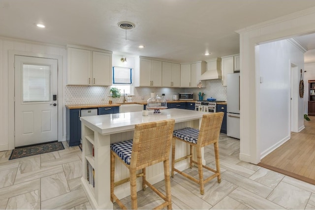 kitchen with decorative backsplash, a kitchen island, light hardwood / wood-style flooring, white cabinets, and premium range hood