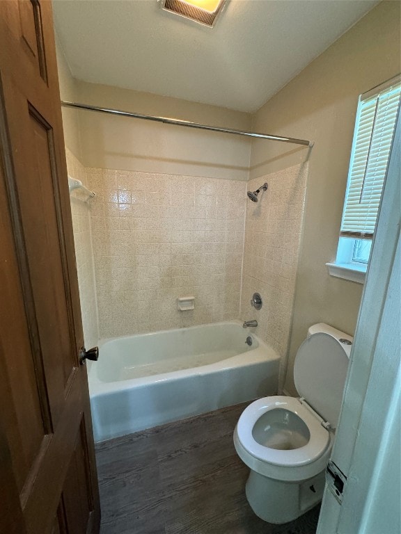 bathroom featuring hardwood / wood-style floors, tiled shower / bath combo, and toilet