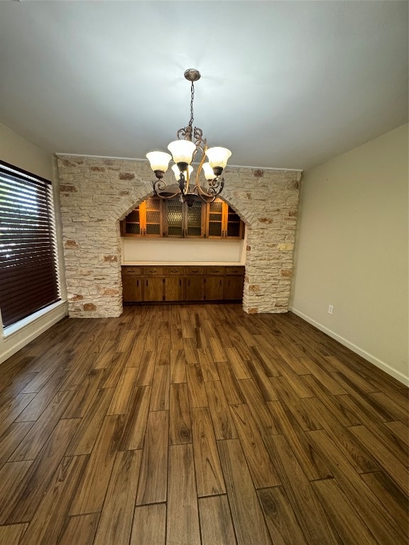 unfurnished dining area featuring a chandelier and dark hardwood / wood-style flooring