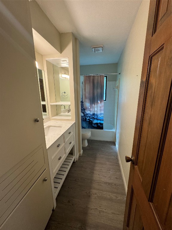 full bathroom with a textured ceiling, hardwood / wood-style flooring, toilet, vanity, and shower / tub combo with curtain