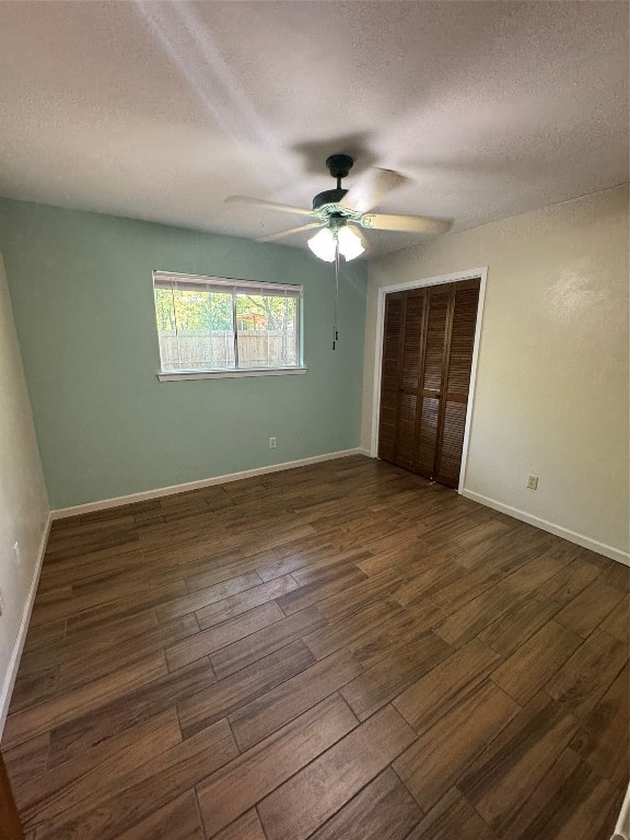 unfurnished bedroom with dark wood-type flooring, ceiling fan, a closet, and a textured ceiling