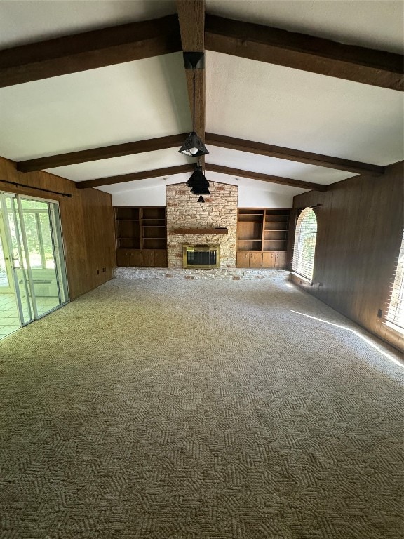 unfurnished living room featuring a fireplace, carpet floors, lofted ceiling with beams, built in shelves, and wood walls