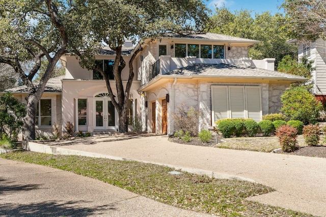 view of front of property featuring stone siding, french doors, a chimney, and an attached garage