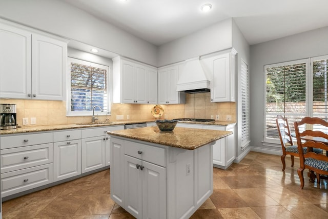 kitchen featuring a kitchen island, a sink, white cabinetry, decorative backsplash, and custom range hood