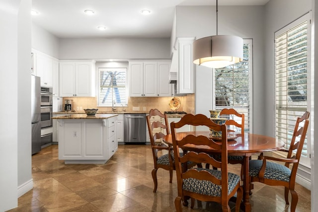 kitchen featuring stainless steel appliances, backsplash, a center island, and white cabinets