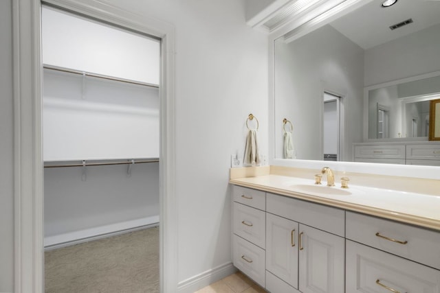 bathroom featuring visible vents, vanity, baseboards, and a spacious closet