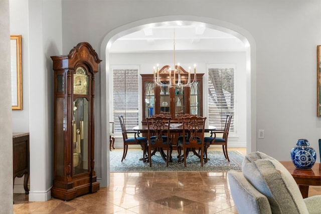 dining room featuring arched walkways, beam ceiling, a notable chandelier, and baseboards