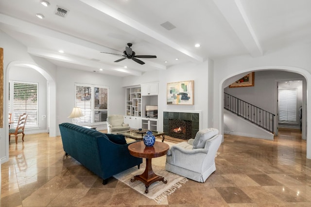 living area with baseboards, a tiled fireplace, visible vents, and beamed ceiling