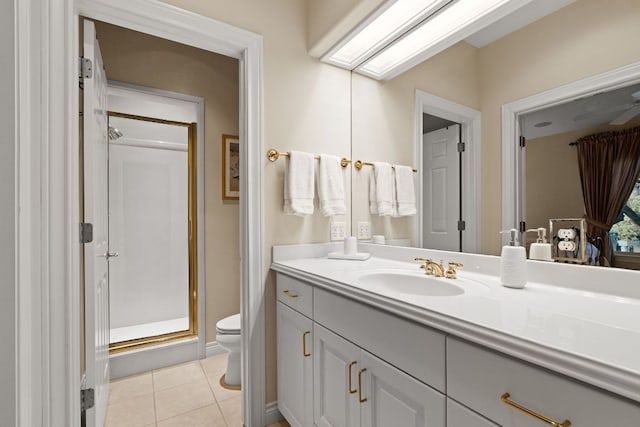 bathroom featuring a skylight, toilet, vanity, a shower stall, and tile patterned floors