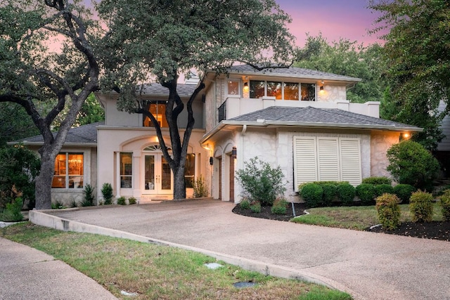 view of front of home with aphalt driveway, french doors, a shingled roof, and stone siding