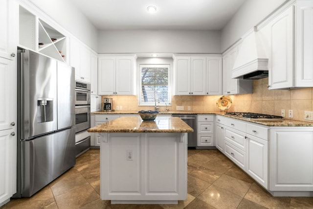 kitchen featuring a center island, tasteful backsplash, appliances with stainless steel finishes, white cabinetry, and premium range hood