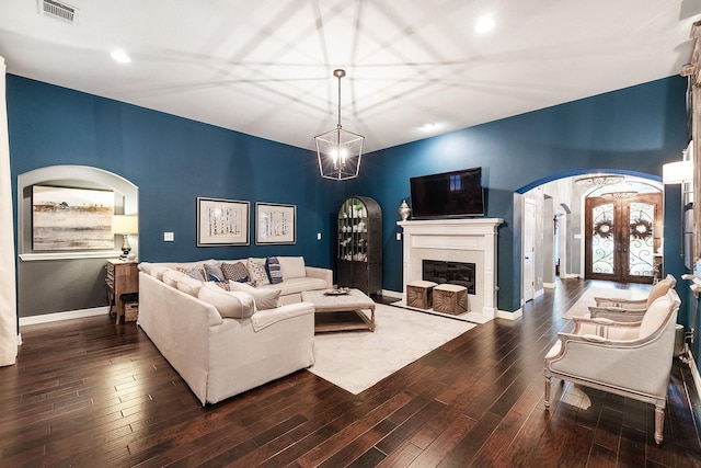 living room with french doors, an inviting chandelier, and dark wood-type flooring