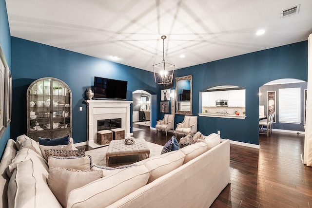 living room with an inviting chandelier and dark wood-type flooring